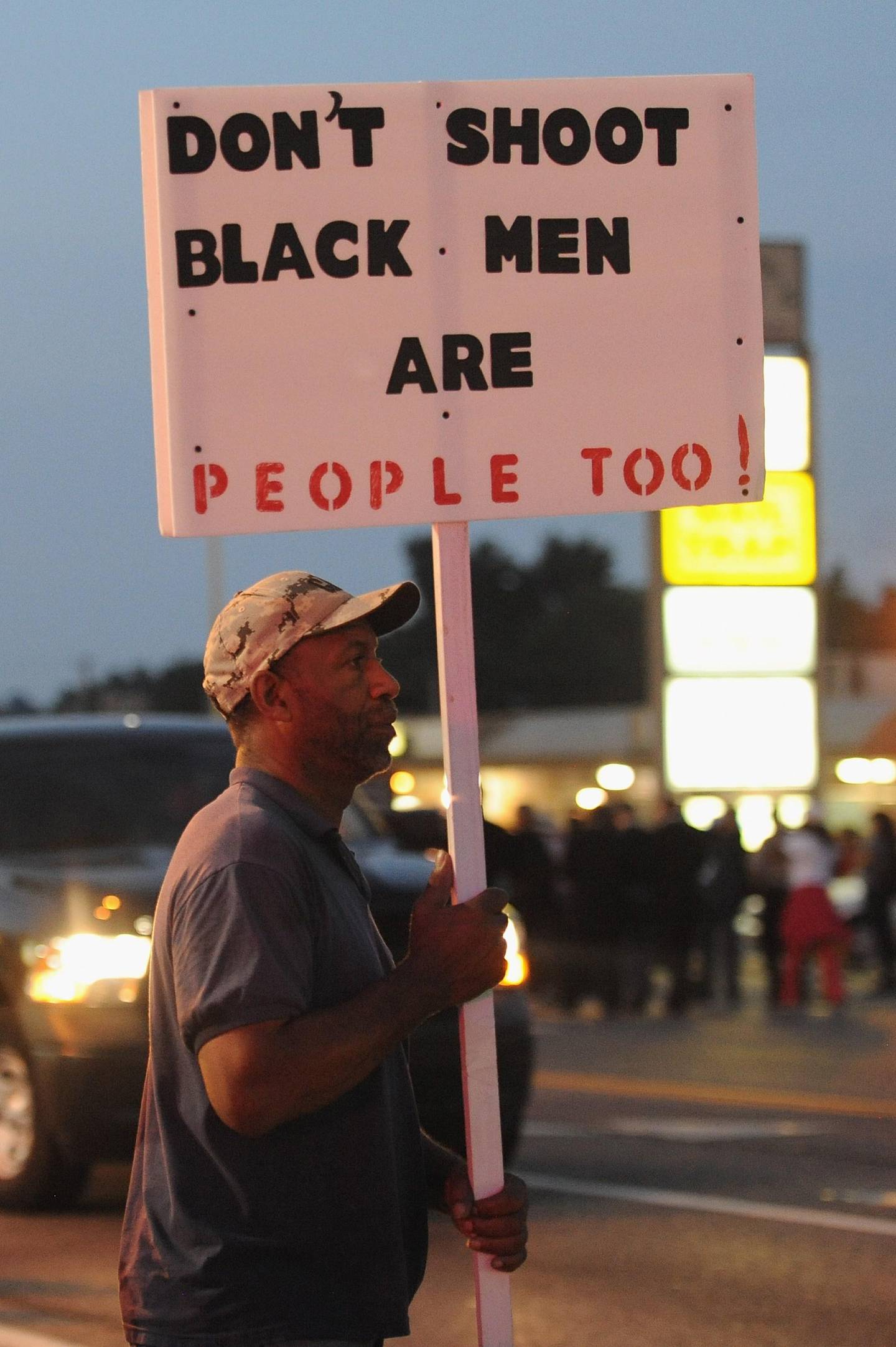A protestor holds a sign during a protest in Ferguson, Missouri on August 18, 2014. Police fired tear gas in another night of unrest in a Missouri town where a white police officer shot and killed an unarmed black teenager, just hours after President Barack Obama called for calm. AFP PHOTO / Michael B. Thomas