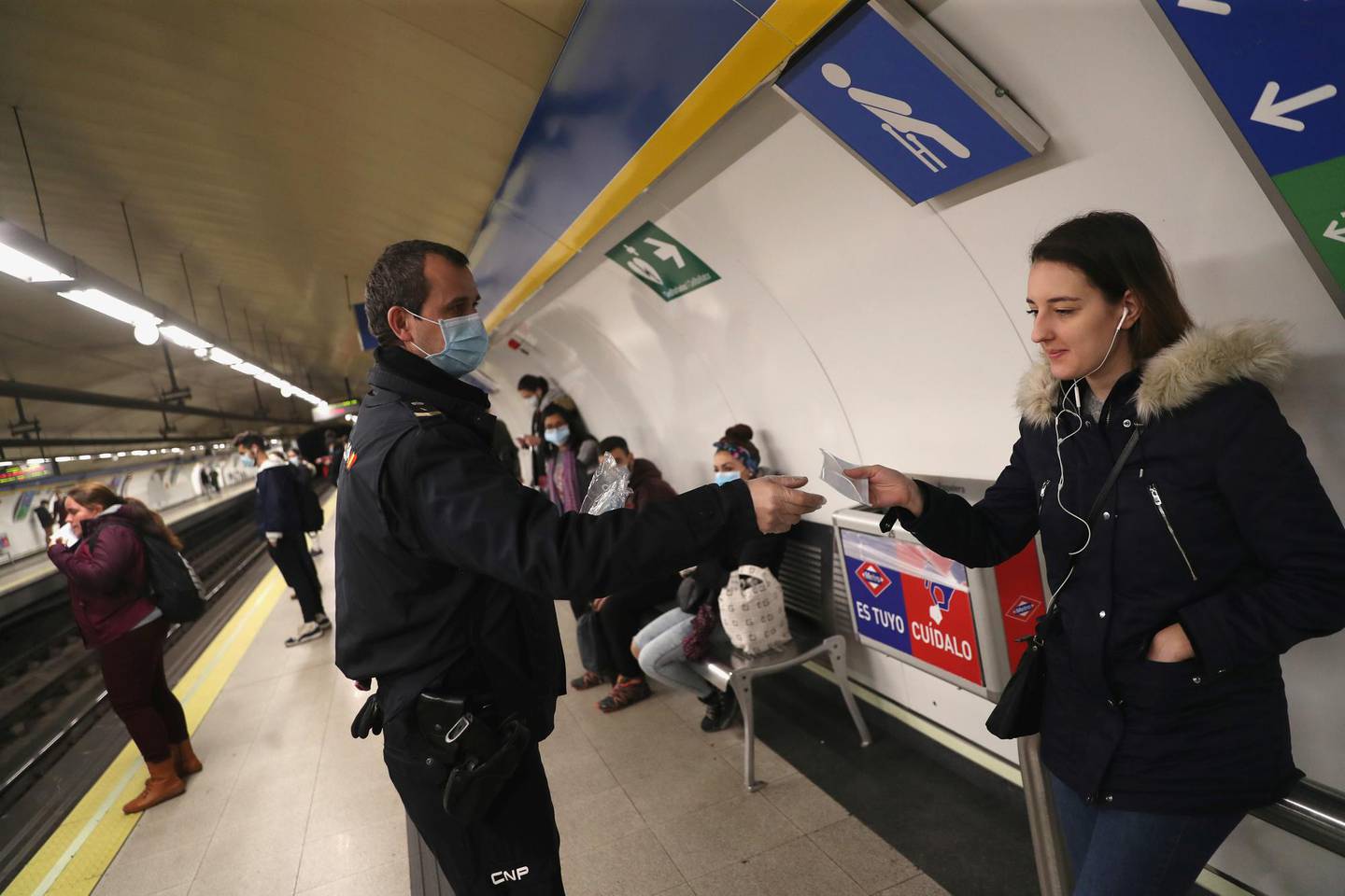 A police officer gives out free protective face masks at a metro station during the lockdown amid the coronavirus disease (COVID-19) outbreak in Madrid, Spain, April 13, 2020. REUTERS/Susana Vera