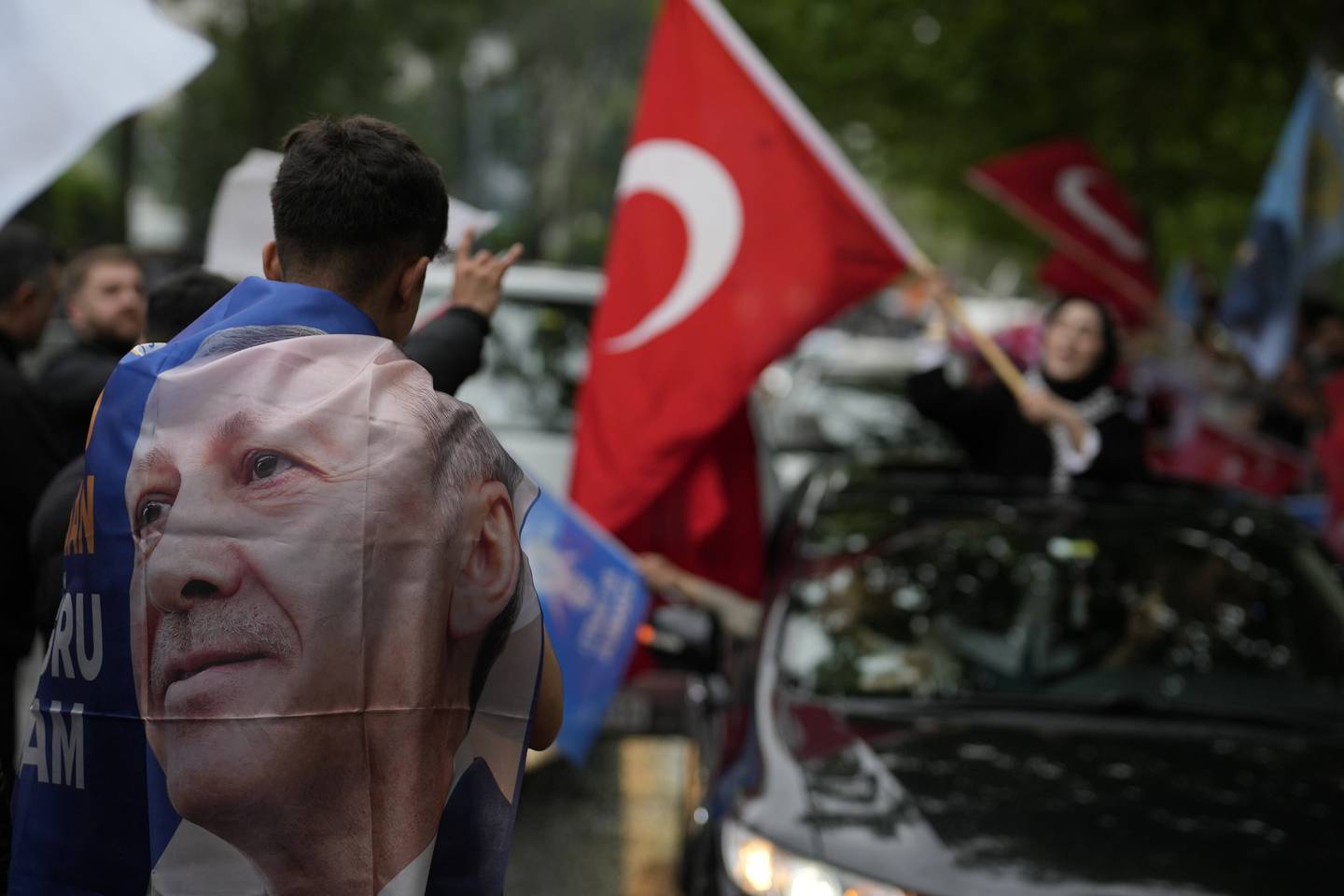 A supporter of the President Recep Tayyip Erdogan waves a Turkish flag at AK Party offices in Istanbul, Turkey, Sunday, May 28, 2023. Erdogan takes lead in unofficial count in Turkey's presidential runoff. (AP Photo/Khalil Hamra)