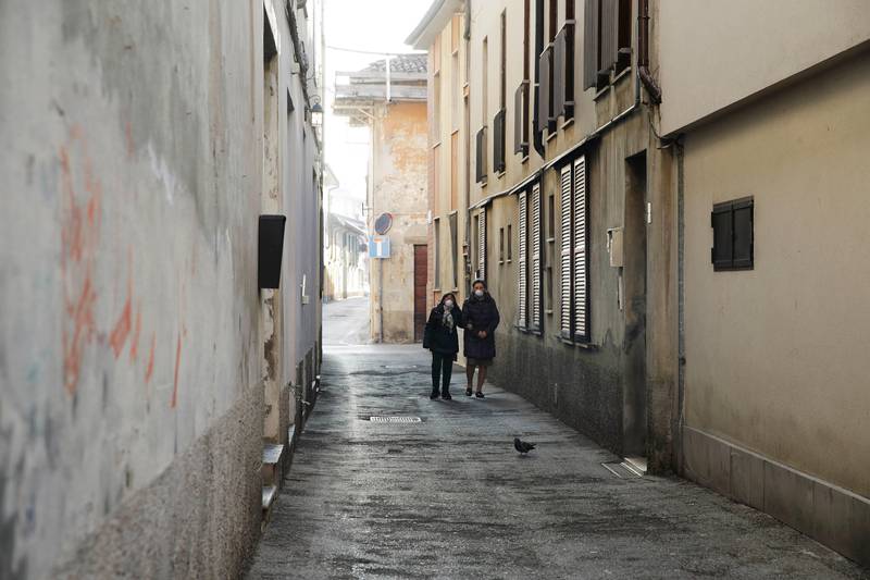 Two women wear masks as they walk in a street in Codogno, near Lodi, Northern Italy, Saturday, Feb. 22, 2020. A dozen towns in northern Italy are on effective lockdown after the new virus linked to China claimed a first fatality in Italy and sickened an increasing number of people. The secondary contagions have prompted local authorities in towns of Lombardy and Veneto to order schools, businesses, and restaurants closed, and to cancel sporting events and Masses. (AP Photo/Luca Bruno)