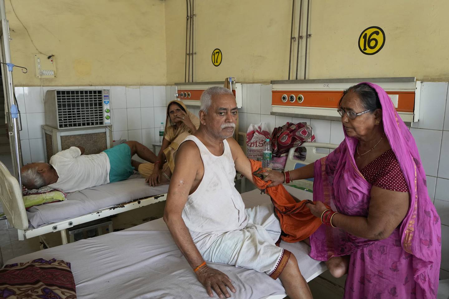 Shiela Mishra tørker hånden til sin syke bror for å holde ham kjølig fra hetebølgen ved hjelp av en våt klut på distriktssykehuset i Ballia, Uttar Pradesh, India.