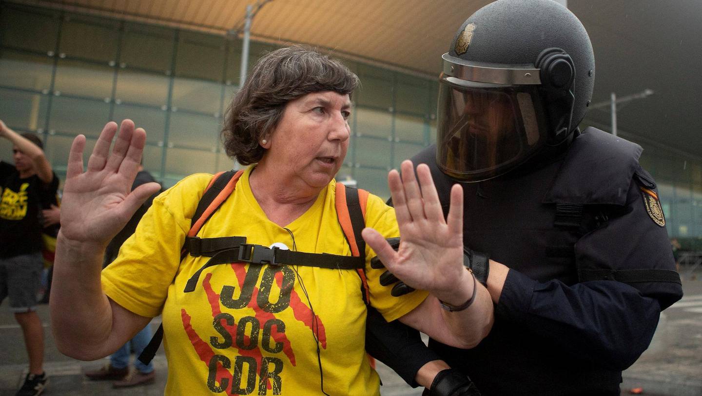 Spansk politi snakker med en demonstrant ved El Prat-flyplassen i Barcelona. FOTO: NTB SCANPIX