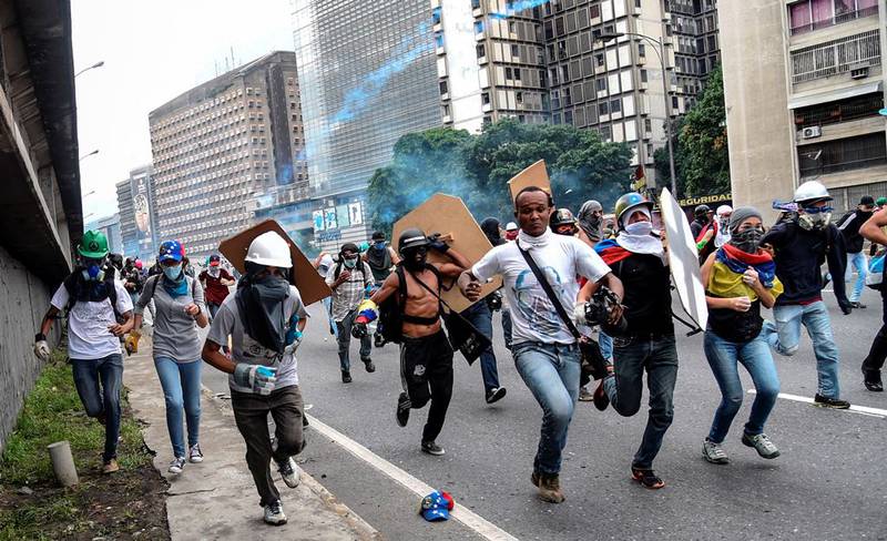 Folk flykter fra sikkerhetsstyrkene under en demonstrasjon mot regjeringen og president Nicolas Maduro i Caracas.