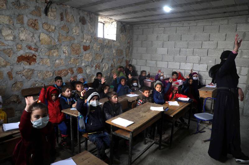 Syrian school children wearing masks due to the Covid-19 pandemic, sit at a makeshift school set up by locals in the village of Ma'arin on the outskirts of Azaz in the rebel-controlled northern countryside of Syria's Aleppo province, on December 8, 2020. (Photo by AAREF WATAD / AFP)