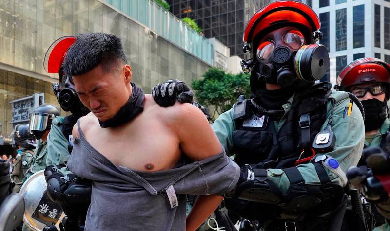 A protester is detained in Central district of Hong Kong on Monday, Nov. 11, 2019. A Hong Kong protester was shot by police Monday in a dramatic scene caught on video as demonstrators blocked train lines and roads during the morning commute. (AP Photo/Vincent Yu)