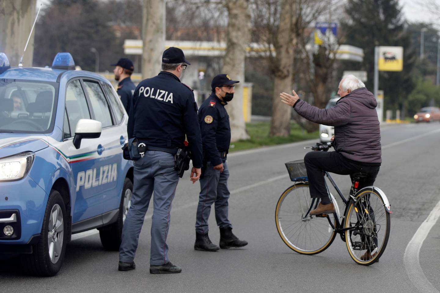 A cyclist talks to police officers controlling movements to and from the cordoned area in Casalpusterlengo, Northern Italy, Sunday, Feb. 23, 2020. A dozen Italian towns saw daily life disrupted after the deaths of two people infected with the virus from China and a pair of case clusters without direct links to the outbreak abroad. A rapid spike in infections prompted authorities in the northern Lombardy and Veneto regions to close schools, businesses and restaurants and to cancel sporting events and Masses. (AP Photo/Luca Bruno)