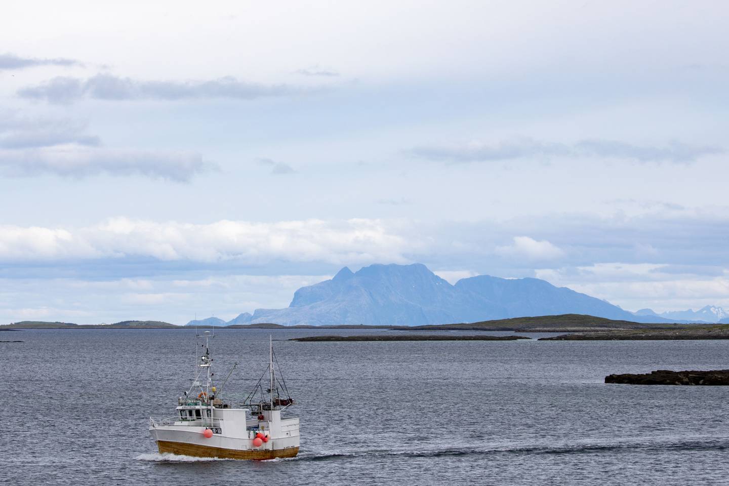 Fiskebåt med krabbar i lasta på veg mot land ved Gardsøya. I bakgrunnen synest Dønnamannen. Foto: Paul Kleiven / NTB / NPK