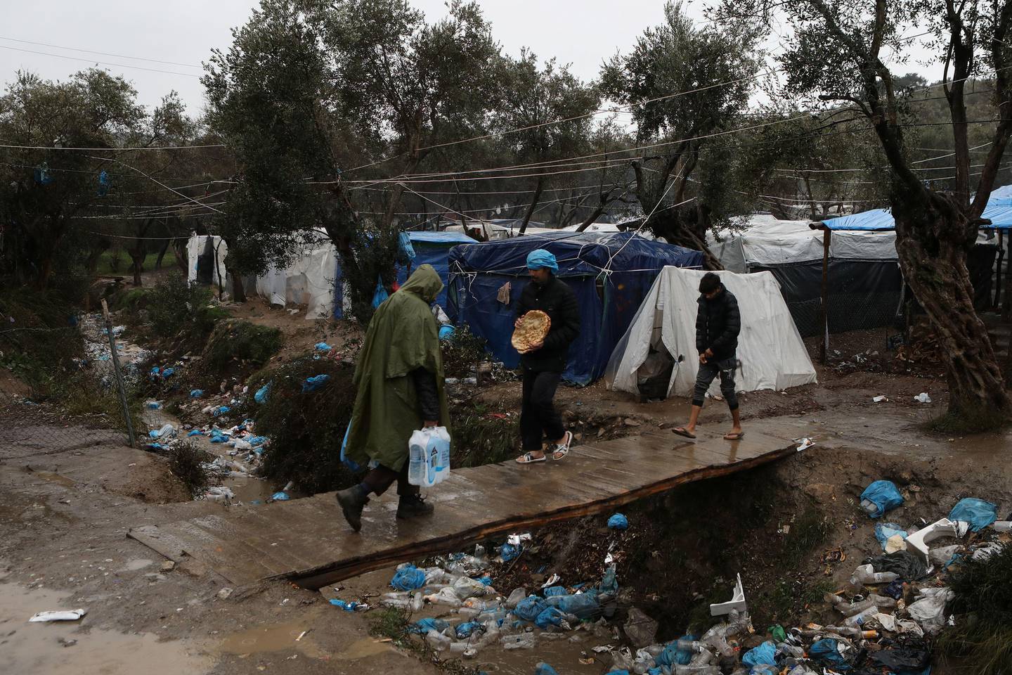 Migrants make their way during heavy rainfall at a temporary camp for refugees and migrants next to the Moria camp on the island of Lesbos, Greece, February 6, 2020. REUTERS/Elias Marcou