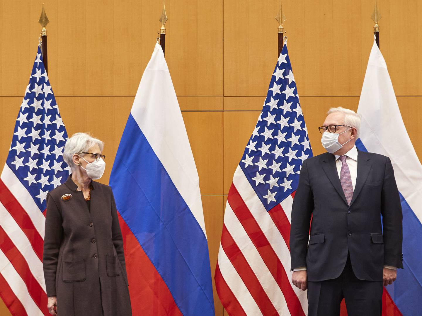 USAs viseutenriksminister Wendy Sherman med sin russiske motpart Sergej Rjabkov foran amerikanske og russiske flagg.