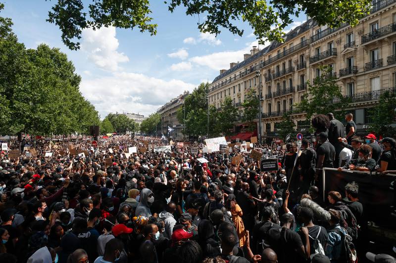 People listen to Assa Traore, right, during a demonstration against police brutality and racism in Paris, France, Saturday, June 13, 2020, organized by supporters of her brother Adama Traore, who died in police custody in 2016 in circumstances that remain unclear despite four years of back-and-forth autopsies. The demonstration is expected to be the biggest of several demonstrations Saturday inspired by the Black Lives Matter movement in the U.S., and French police ordered the closure of freshly reopened restaurants and shops along the route fearing possible violence. (AP Photo/Thibault Camus)