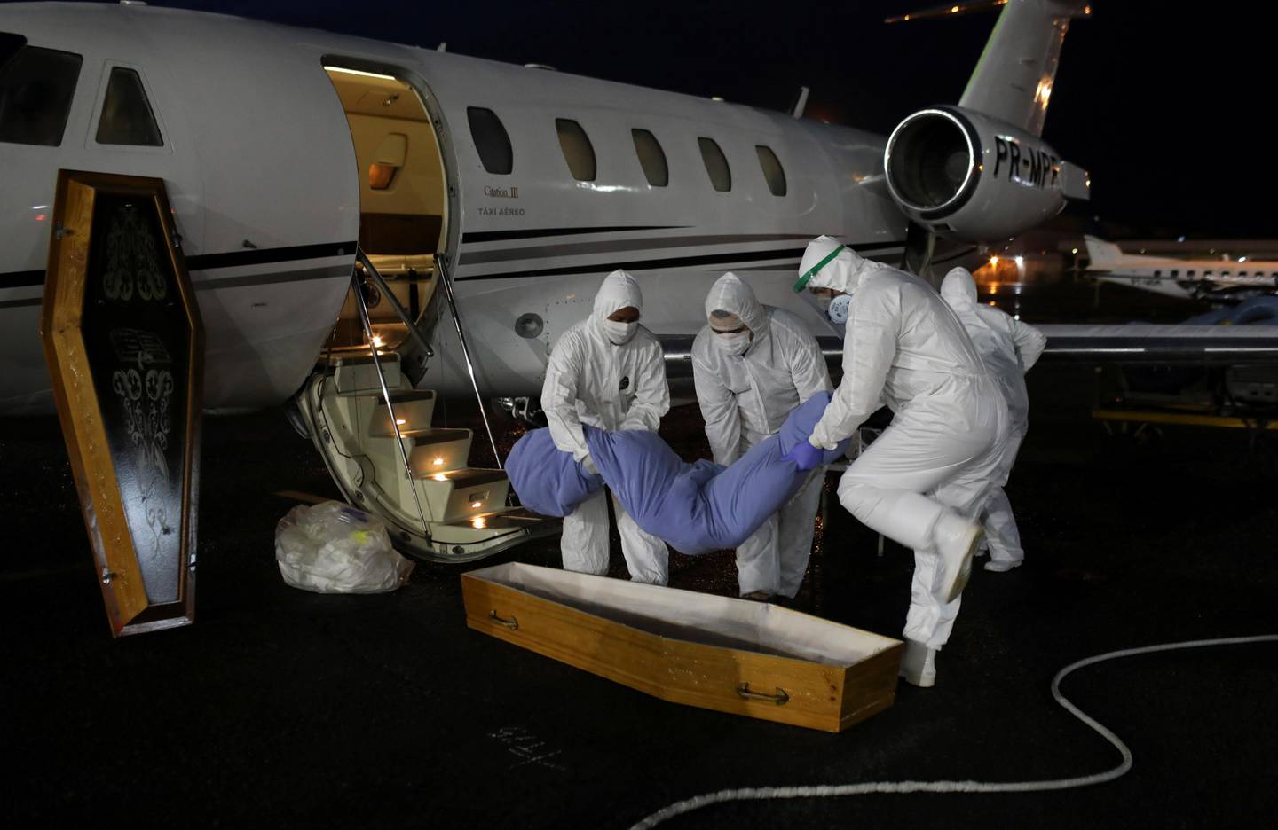 Healthcare workers on protective clothing carry the body of Laureano Ferraz, 78, a Wanano indigenous man who passed away due to the coronavirus disease (COVID-19), after arriving by an ICU jet from Sao Gabriel da Cachoeira to Manaus, Brazil, May 18, 2020. REUTERS/Bruno Kelly