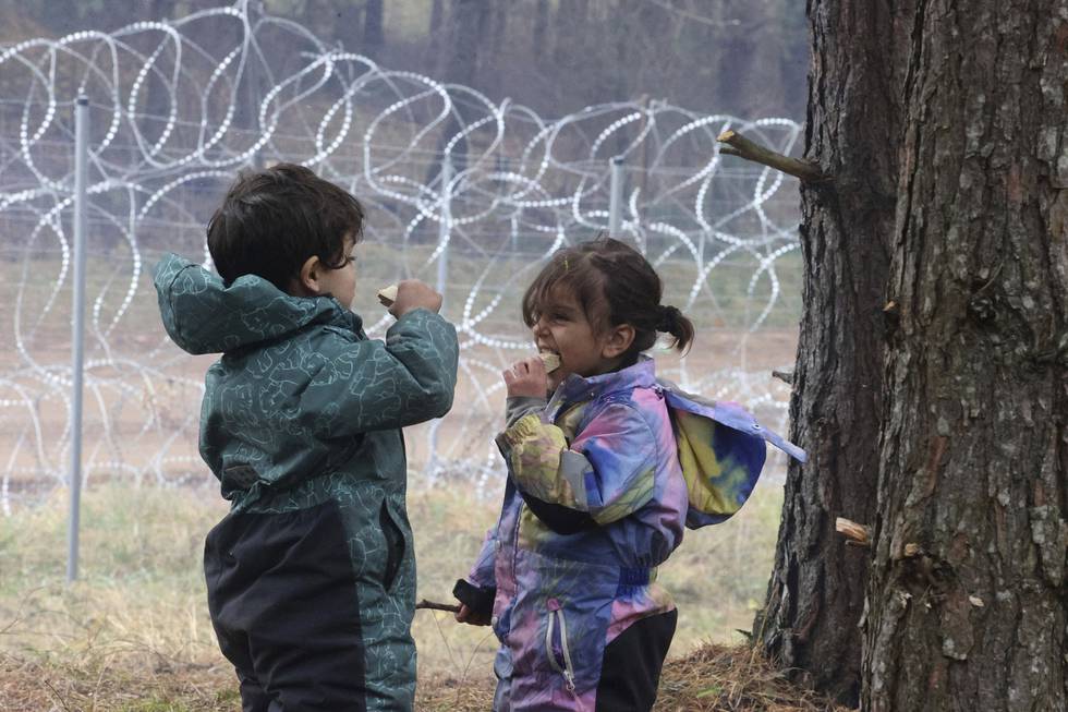 Barn er blant over 2.000 migranter og flyktninger som ifølge hviterussiske myndigheter er samlet nær grensa til Polen, her i nærheten av Grodno i Hviterussland lørdag. Foto: Leonid Shcheglov/BelTA pool photo via AP / NTB