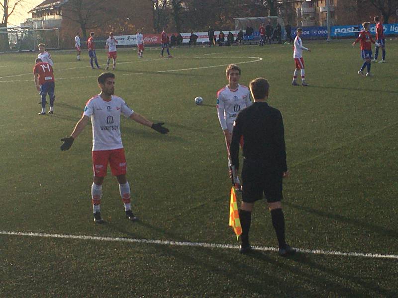 Fredrikstad-spillerne tar en lang diskusjon med assistentdommer mens hoveddommer er opptatt med å diskutere med laglederbenken på motsatt side.