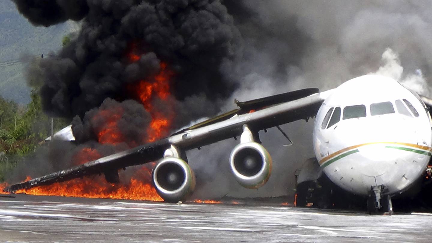 Smoke billows from a British-made BAe 146 cargo plane that caught fire while being unloaded at the airport in Wamena, Papua province, Indonesia, Wednesday, May 8, 2013. An official said that the plane caught fire after a drum of oil fell from the aircraft and somehow sparked the fire. (AP Photo)