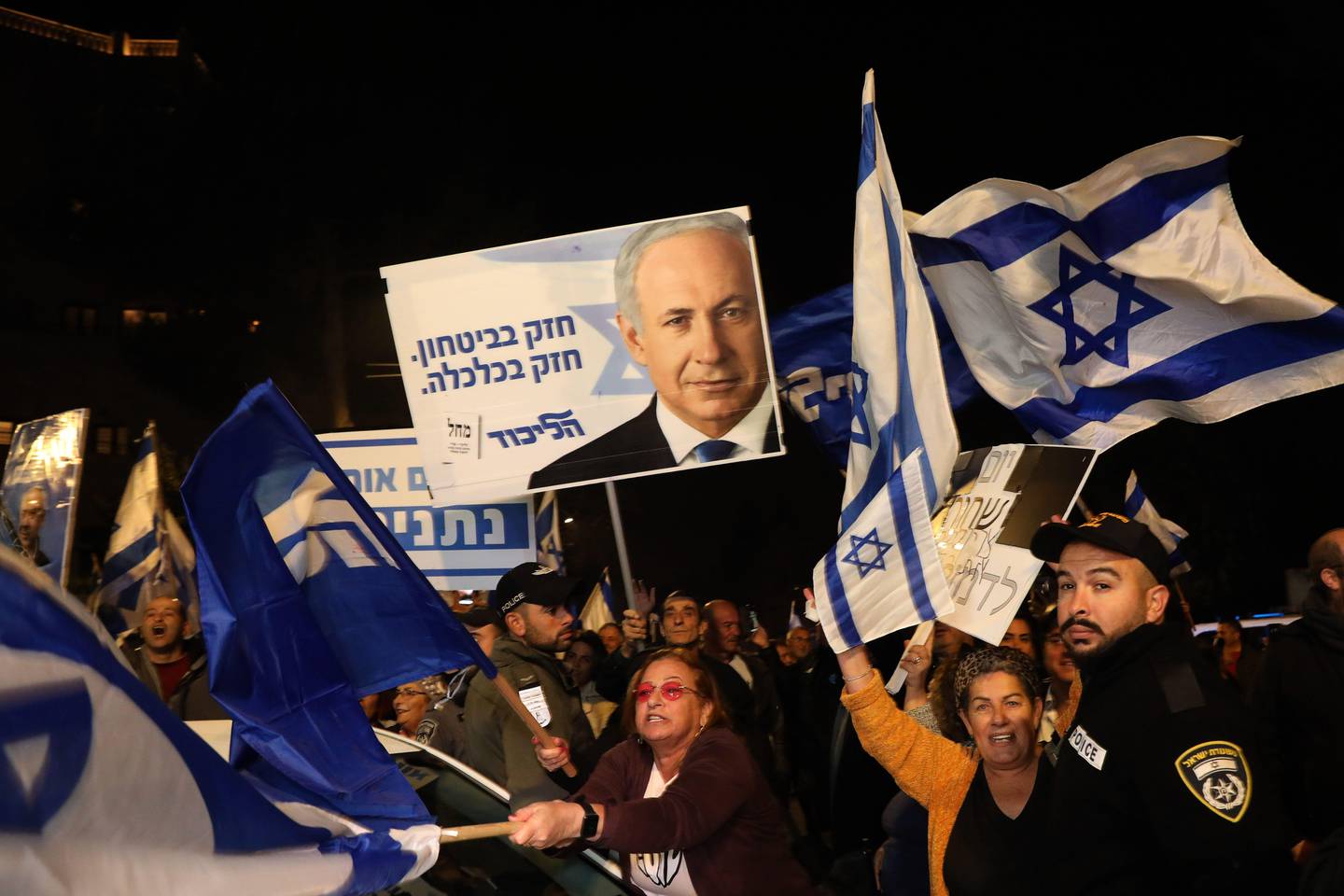Supporters of Israeli Prime Minister Benjamin Netanyahu wave flags and placards as they rally to express their solidarity, outside his Jerusalem office on November 23, 2019. - Benjamin Netanyahu's indictment on corruption charges a day earlier prompted speculation that the end of his decade-long tenure was nigh, though several key allies expressed support for the beleaguered Israeli premier. (Photo by GALI TIBBON / AFP)