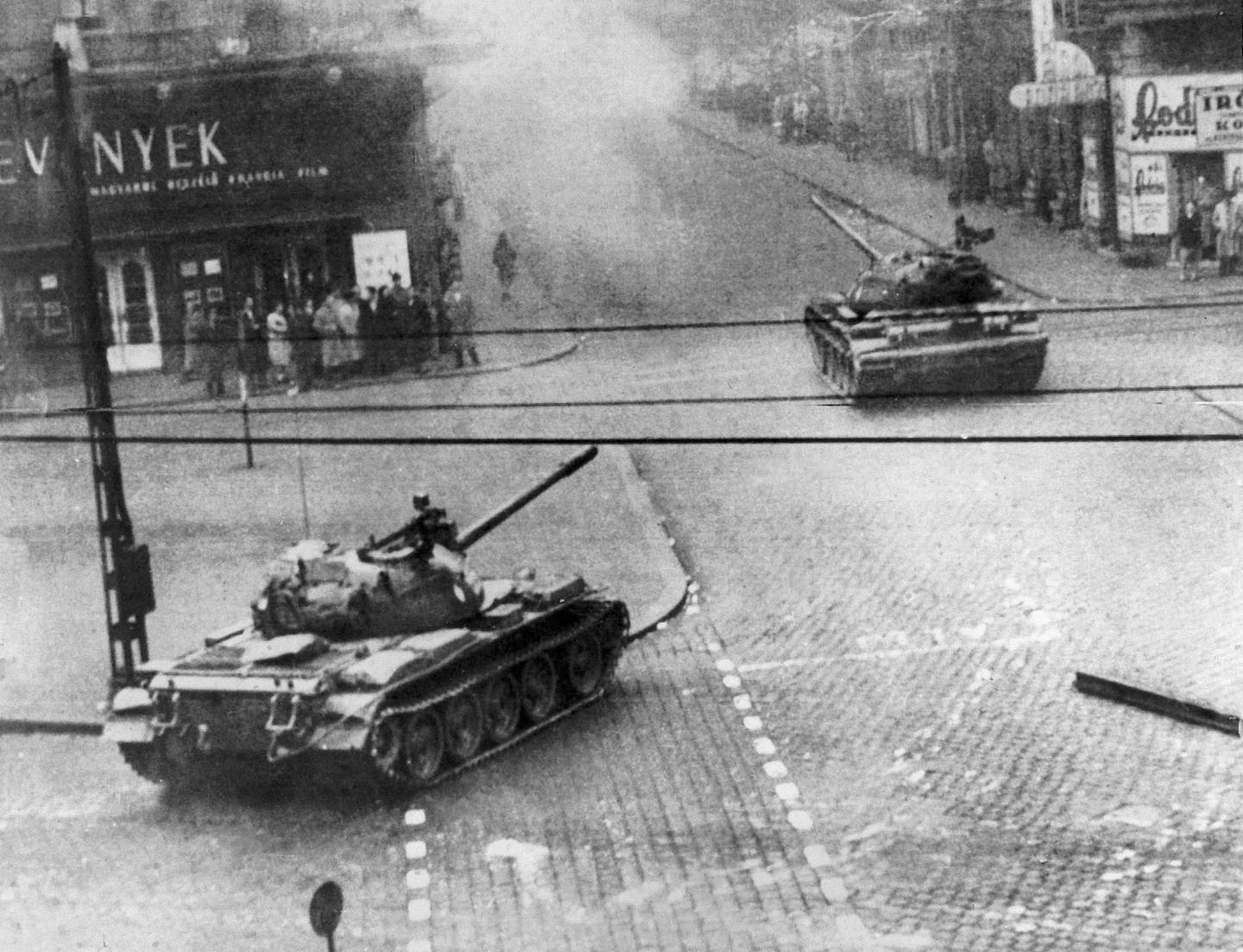 Soviet-built tanks wheel into action in a smoke-filled Budapest street in Hungary's flaring revolution against communist satellite government, Oct. 27, 1956. Citizens stand close to building fronts to stay out of the line of fire. Many Hungarian Army units reportedly have gone over to the rebels in fighting against police and units of the Soviet Red Army. (AP Photo)