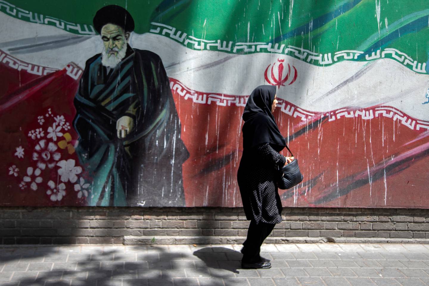 En iransk kvinne går foran et veggmaleri av tidligere leder ayatolla Ruhollah Khomeini i Tehran.