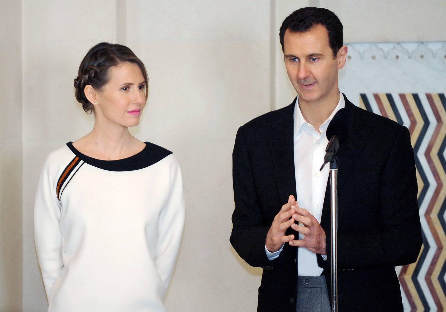 (FILES) This file handout photo released by the official Syrian Arab News Agency (SANA) shows Syrian President Bashar al-Assad (R) speaking next to his wife Asma as they receive members of the army and their mother's to celebrate Mother's Day in the capital Damascus on March 21, 2016. - When the Arab revolts that were sweeping the region and toppling autocrats like dominoes reached Syria, Bashar al-Assad's days at the helm looked numbered. Ten years on however, he has defied the odds, surviving international isolation and the temporary loss of two thirds of the national territory to claw his way back into relevance and hold on to power. It seemed doubtful in March 2011 when protests broke out in Syria, that his ruling Alawite minority would be capable of withstanding the tide of uprisings dramatically reshaping the region. (Photo by - / various sources / AFP) / == RESTRICTED TO EDITORIAL USE - MANDATORY CREDIT "AFP PHOTO / HO / SANA" - NO MARKETING NO ADVERTISING CAMPAIGNS - DISTRIBUTED AS A SERVICE TO CLIENTS ==