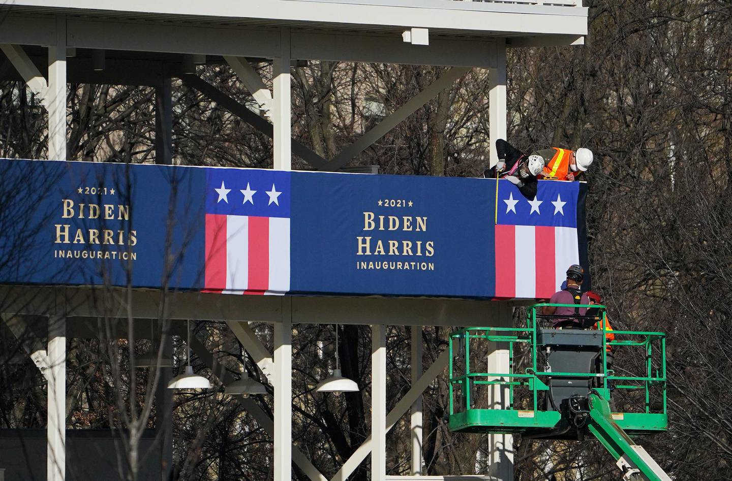 Workers adjust the bunting on a riser across from the White House in Washington, DC on January 14, 2021. - The center of Washington was on lockdown Thursday as more than 20,000 armed National Guard troops were being mobilized due to security concerns ahead of the presidential inauguration of Joe Biden. (Photo by MANDEL NGAN / AFP)