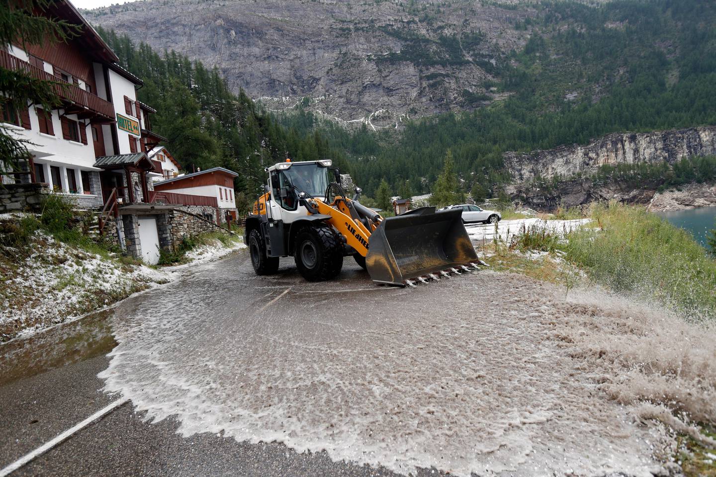 A worker uses a snow shovel to clean the road of the nineteenth stage of the Tour de France cycling race over 126,5 kilometers (78,60 miles) with start in Saint Jean De Maurienne and finish in Tignes, France, Friday, July 26, 2019. Tour de France organizers stopped Stage 19 of the race because of a hail storm as Julien Alaphilippe lost his yellow jersey to Egan Bernal. (AP Photo/Thibault Camus)