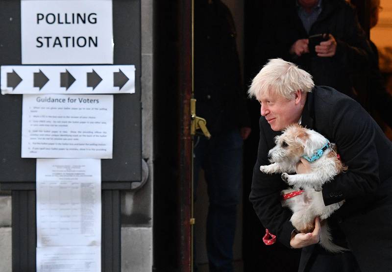 Britain's Prime Minister Boris Johnson poses with his dog Dilyn as he leaves from a Polling Station, after casting his ballot paper and voting, in central London on December 12, 2019, as Britain holds a general election. (Photo by DANIEL LEAL-OLIVAS / AFP)