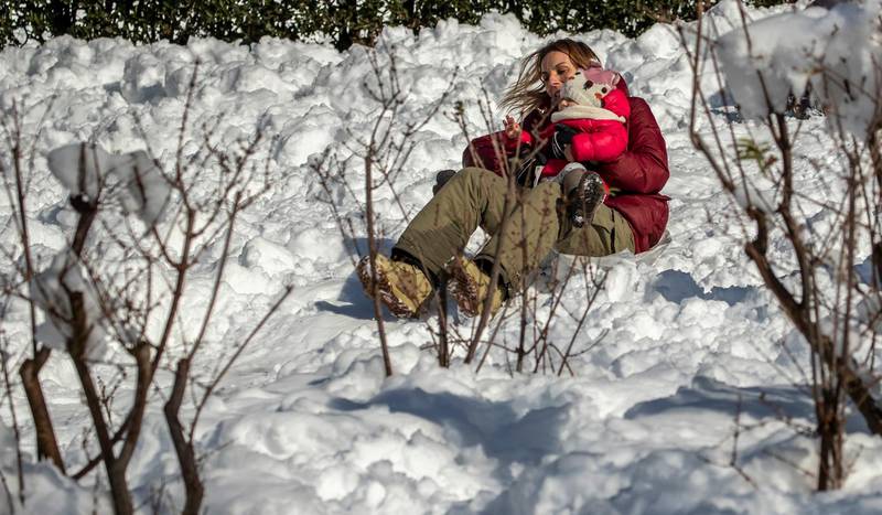 A woman child enjoy the snow in downtown Madrid, Spain, Sunday, Jan. 10, 2021.  A large part of central Spain including the capital of Madrid are slowly clearing snow after the country's worst snowstorm in recent memory. (AP Photo/Manu Fernandez)