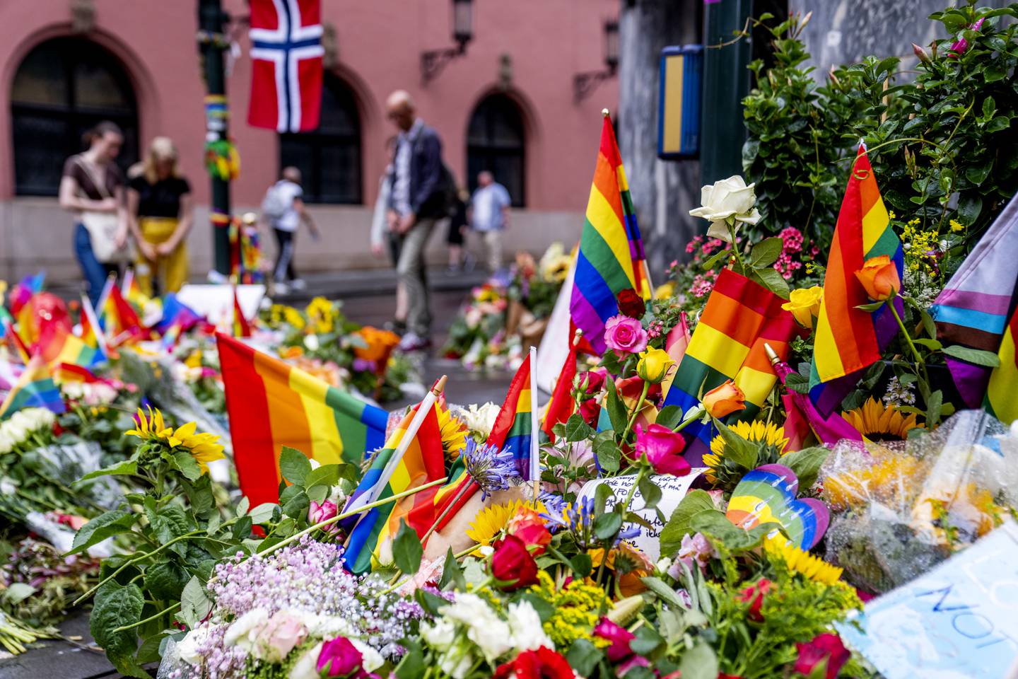Folk la ned blomster og pride-flagg etter angrepet 25. juni i fjor.
