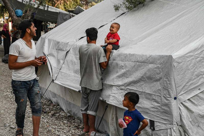 Refugees and migrants are pictured in a improvised tents camp near the refugee camp of Moria in the island of Lesbos on June 21, 2020. - Greece's announcement that it was extending the coronavirus lockdown at its migrant camps until July 5, cancelling plans to lift the measures on June 22, coincided with World Refugee Day on June 27, 2020. (Photo by ARIS MESSINIS / AFP)