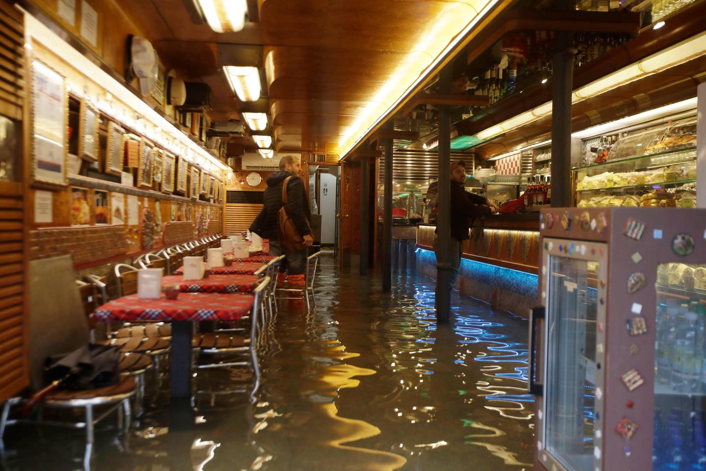 People stand inside a flooded cafe' on the occasion of a high tide, in Venice, Italy, Tuesday, Nov. 12, 2019. The high tide reached a peak of 127cm (4.1ft) at 10:35am while an even higher level of 140cm(4.6ft) was predicted for later Tuesday evening. (AP Photo/Luca Bruno)