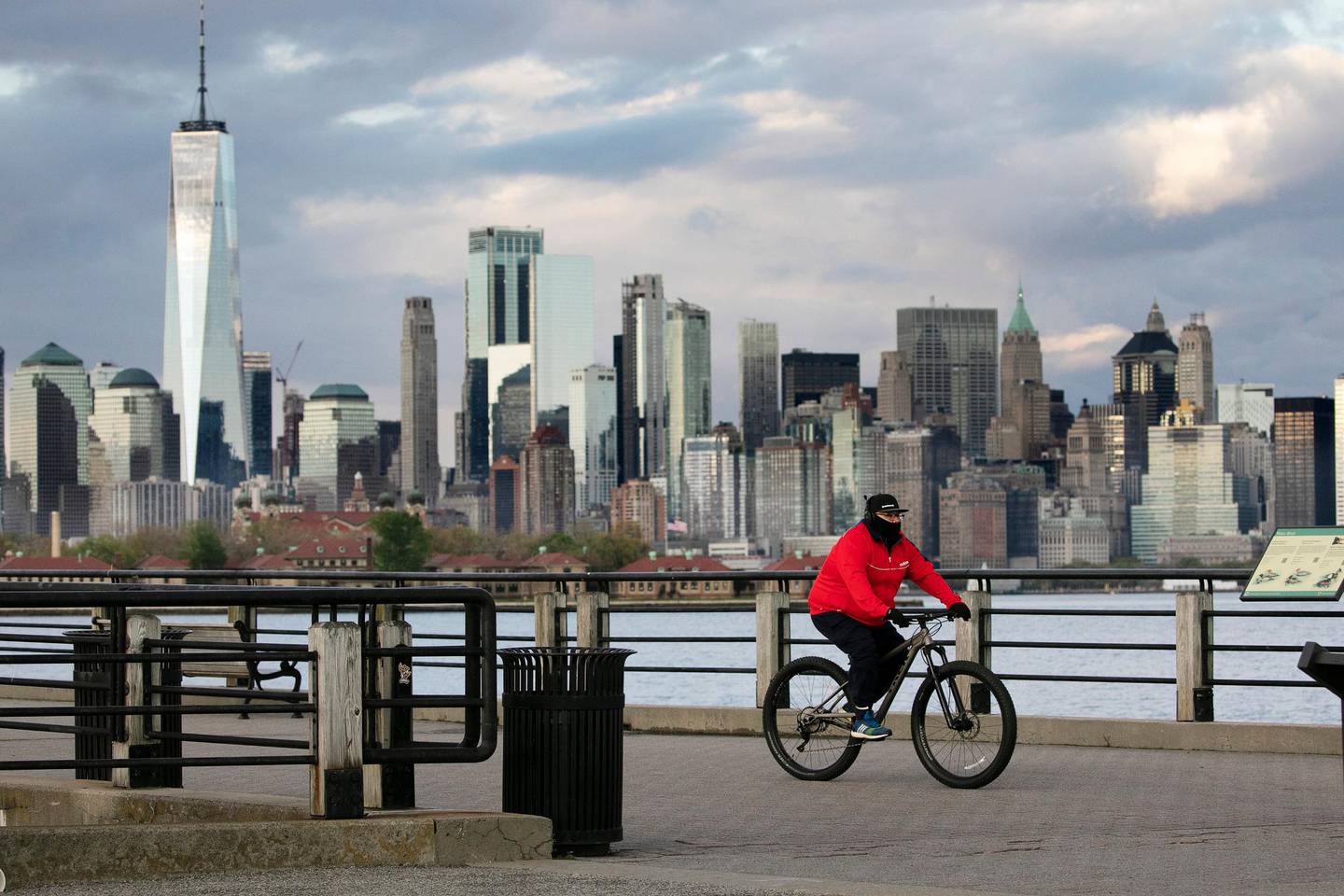 A cyclist wears a mask as he bikes in Liberty State Park, Monday, May 11, 2020, in Jersey City, N.J., during the coronavirus pandemic. Behind him is some of the New York skyline. Gov. Phil Murphy said on Monday that New Jersey will soon have what he called "hard dates" for the start of the reopening process. (AP Photo/Mark Lennihan)