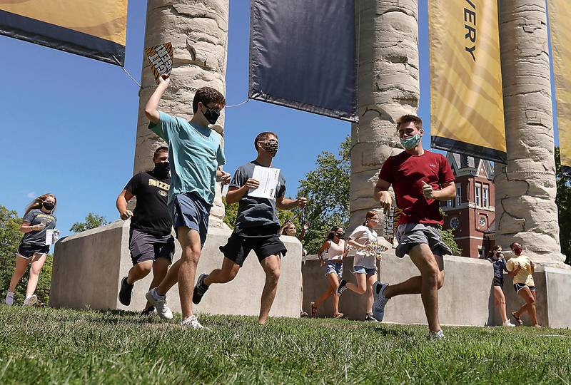 Incoming freshmen run through the University of Missouri columns on Aug. 19, 2020, for the Tiger Walk, in Columbia, Mo. As waves of schools and businesses around the country are cleared to reopen, college towns are moving toward renewed shutdowns because of too many parties and too many COVID-19 infections among students. (Owen Ziliak/Missourian via AP)