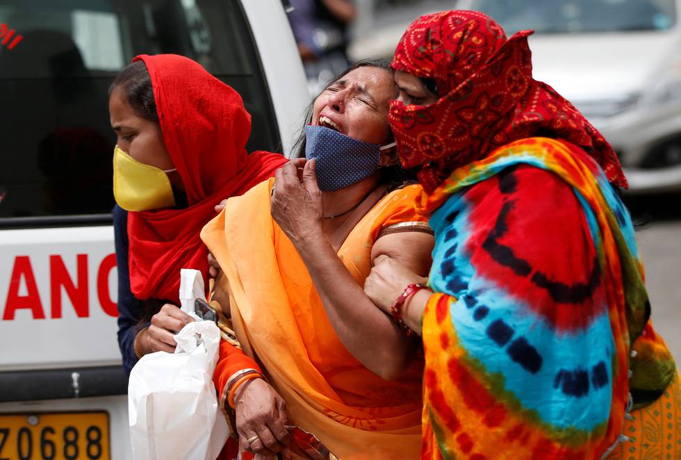 En kvinne blir trøstet utenfor et sykehus i Ahmedabad i India etter at mannen hennes døde av covid-19.