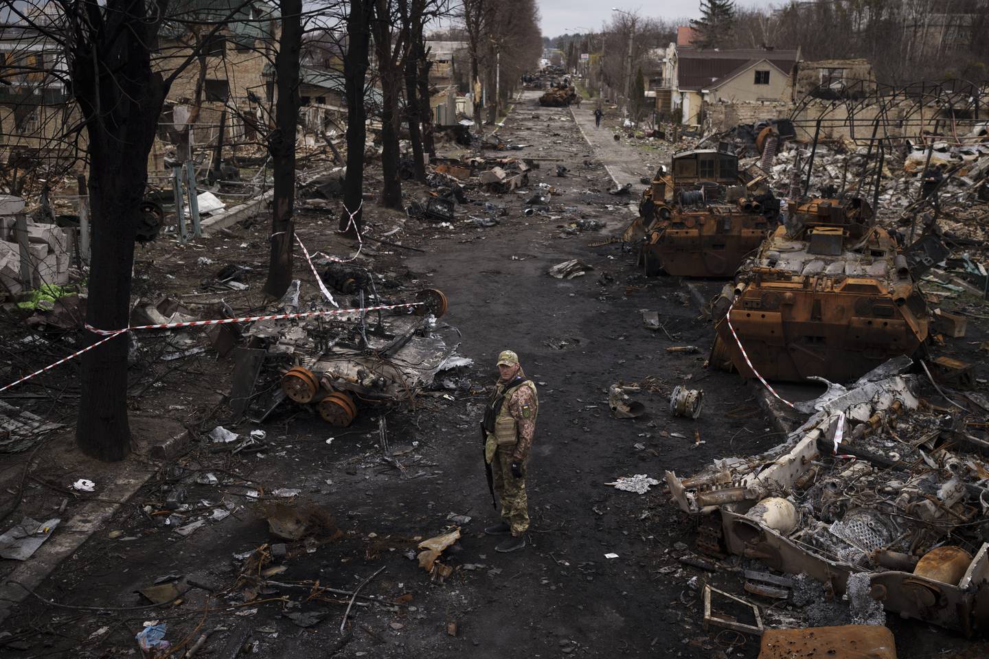 En ukrainsk soldat står mellom ødelagte russiske tanks i Butsja 6. april 2022.