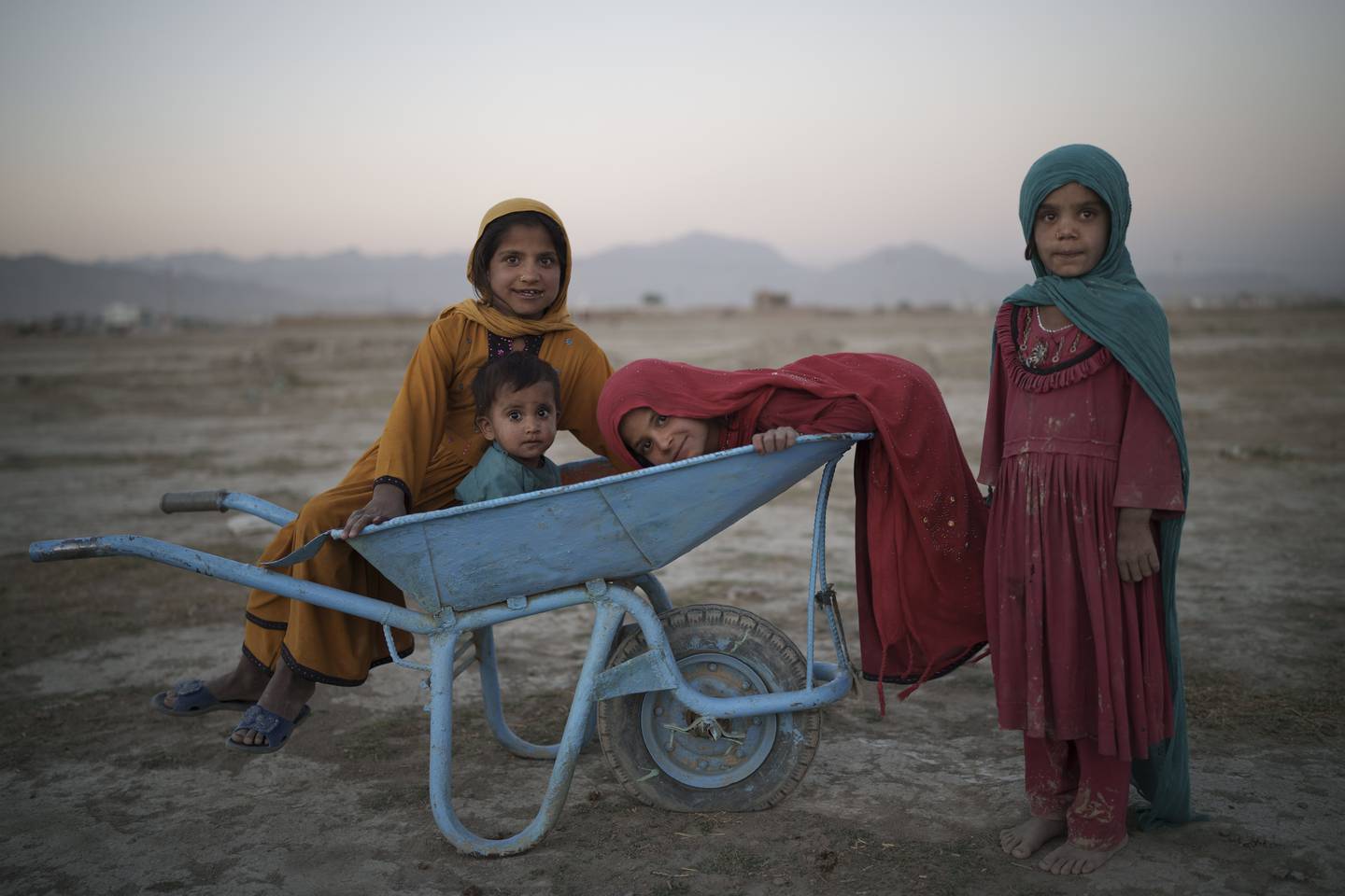 Fire barn poserer for fotografen mens de leker i en leit for internt fordrevne i Kabul.