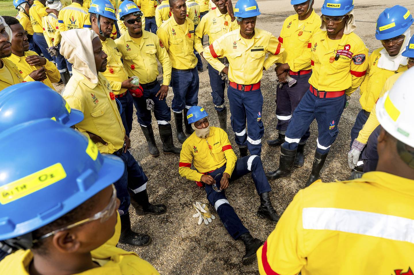 Sør-Afrikanske brannmenn i gule jakker stimler sammen til et sikkerhetsmøte i forbindelse med skogbranner i Canada.