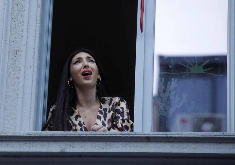 Den italienske operasangeren Laura Baldassari lener seg ut av vinduet og synger moto koronaviruset         av sine lungers full kraft.                                Foto: NTB scanpix