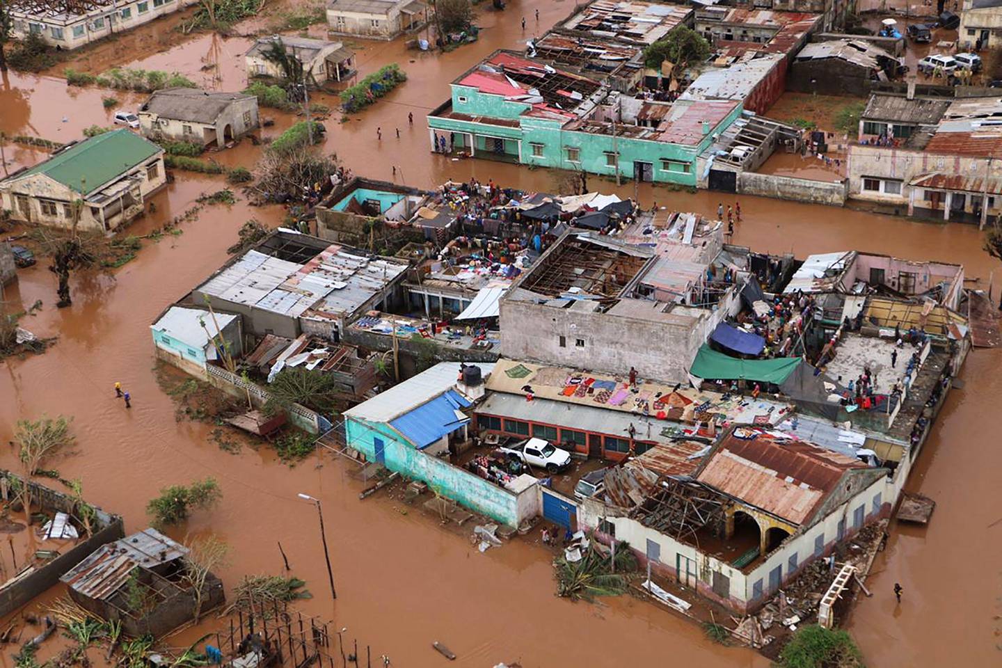 TOPSHOT - Residents stand on rooftops in a flooded area of Buzi, central Mozambique, on March 20, 2019, after the passage of cyclone Idai. - International aid agencies raced on March 20 to rescue survivors and meet spiralling humanitarian needs in three impoverished countries battered by one of the worst storms to hit southern Africa in decades. Five days after tropical cyclone Idai cut a swathe through Mozambique, Zimbabwe and Malawi, the confirmed death toll stood at more than 300 and hundreds of thousands of lives were at risk, officials said. (Photo by ADRIEN BARBIER / AFP)