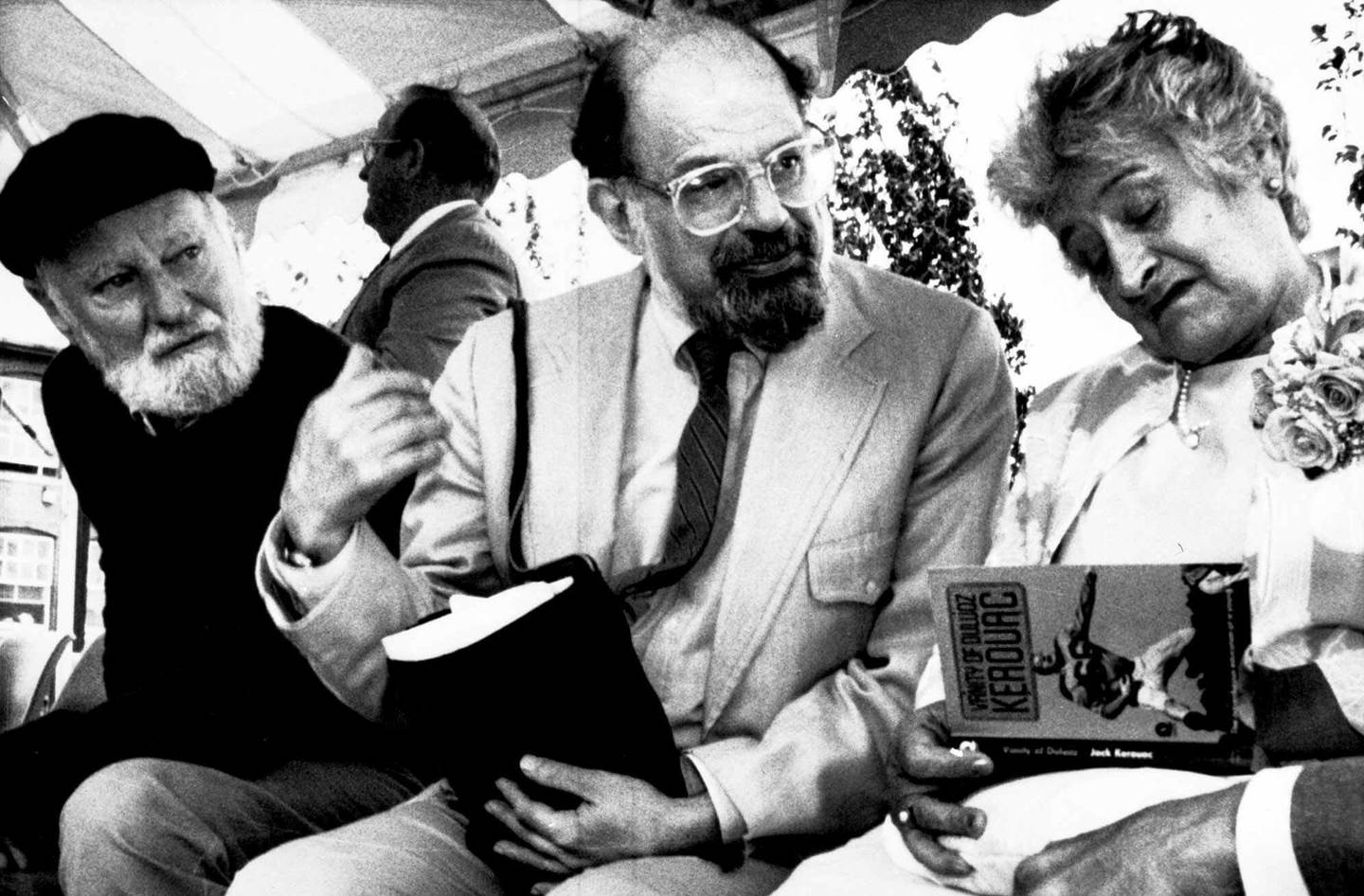Poets Lawrence Ferlinghetti, left, and Allen Ginsberg, center, look on with Stella Kerouac, right, in this June 25, 1988 photo. Kerouac autographs one of her late husband's books, during the dedication of the Jack Kerouac Commerative, a work of public art, in Lowell, Massachusetts' historic district.        (AP Photo)