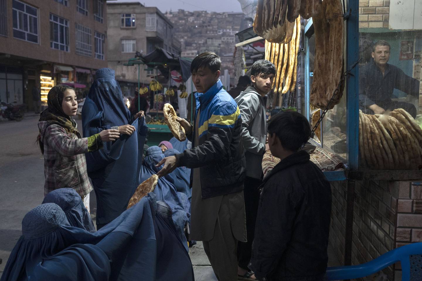 Bruka-kledte kvinner får brød ved et bakeri i Kabul i desember i fjor.