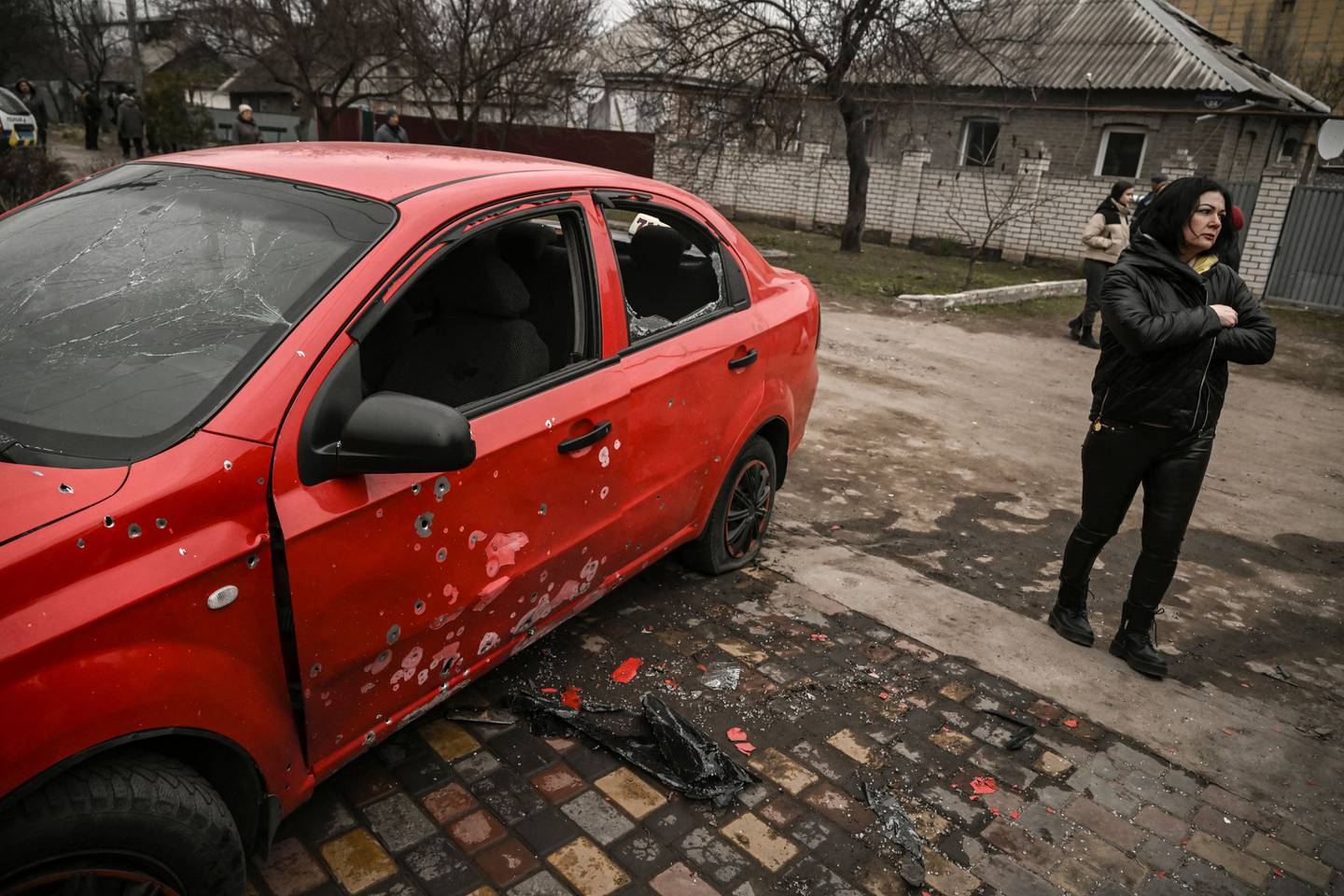 A woman stands next to a damaged car after a cluster bomb strike in Kramatorsk in the Donbas region on March 18, 2023. (Photo by Aris Messinis / AFP)