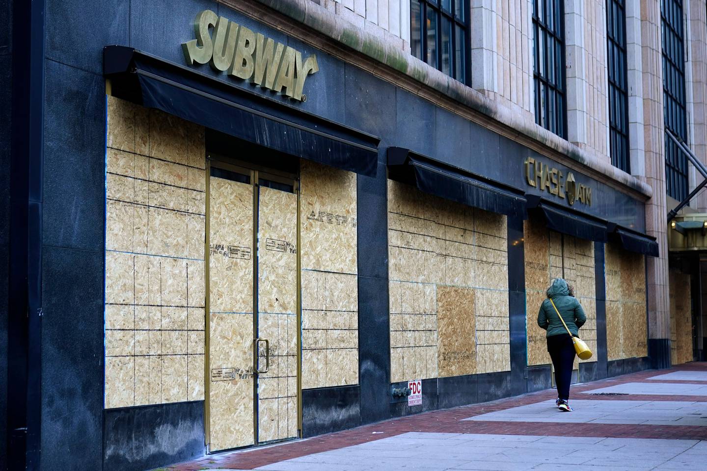 A woman walks past boarded-up businesses on the eve of the 2020 General Election in the United States, Monday, Nov. 2, 2020, in Philadelphia. (AP Photo/Matt Slocum)
