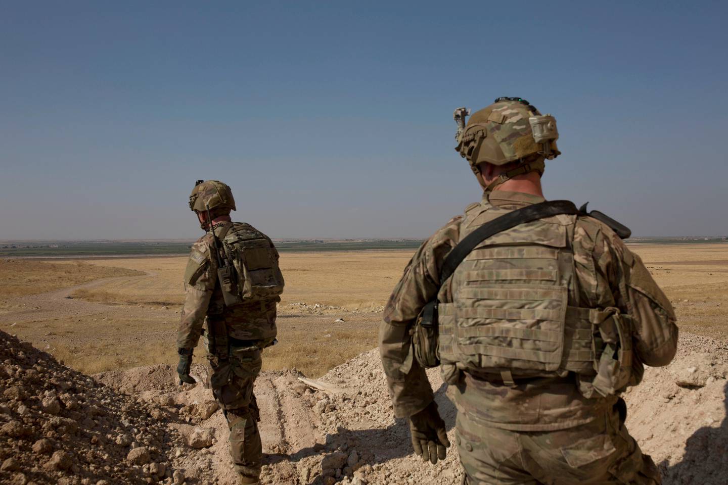 FILE - In this Sept. 6, 2019 file photo, U.S. soldiers survey the the safe zone between Syria and the Turkish border near Tal Abyad, Syria, on a joint patrol with the Tax Abyad Military Council, affiliated with the U.S.-backed Syrian Democratic Forces. Defense Secretary Mark Esper says that under the current plan all U.S. troops leaving Syria will go to western Iraq, and that the military will continue to conduct operations against the Islamic State group to prevent a resurgence in that country. (AP Photo/Maya Alleruzzo, File)
