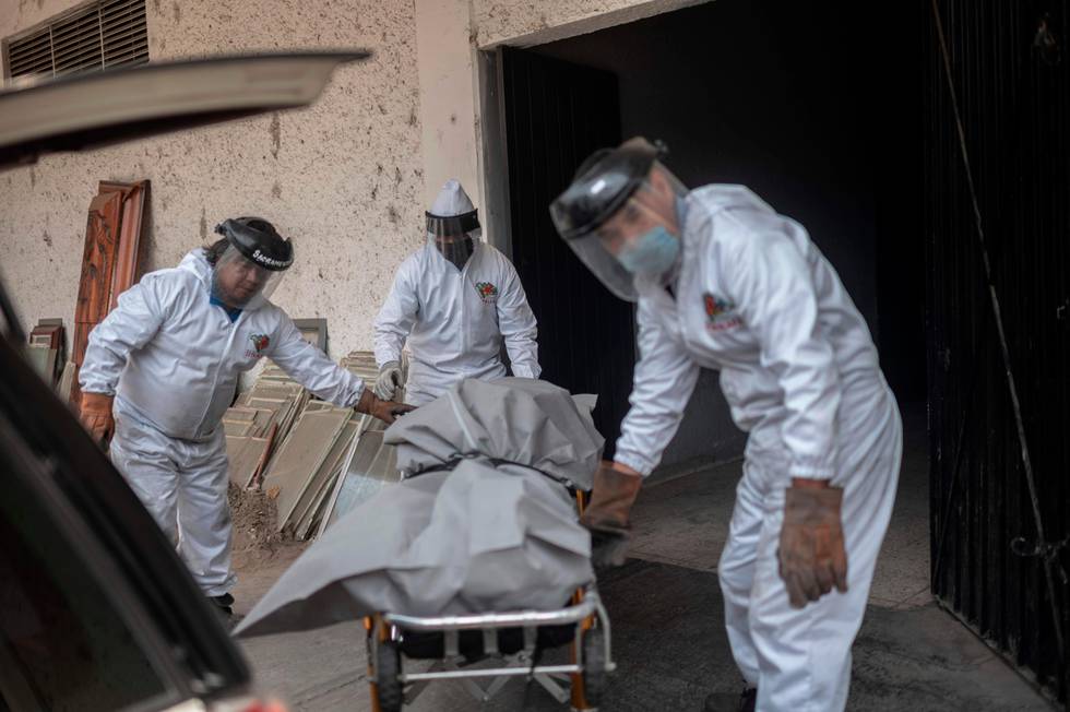 Mortuary workers move the body of a COVID-19 victim at a crematorium in the Iztapalapa neighborhood, in Mexico City, on April 24, 2020. - By Thursday, Mexico had registered just over 11, coronavirus cases and more than 1,000 deaths. (Photo by PEDRO PARDO / AFP)