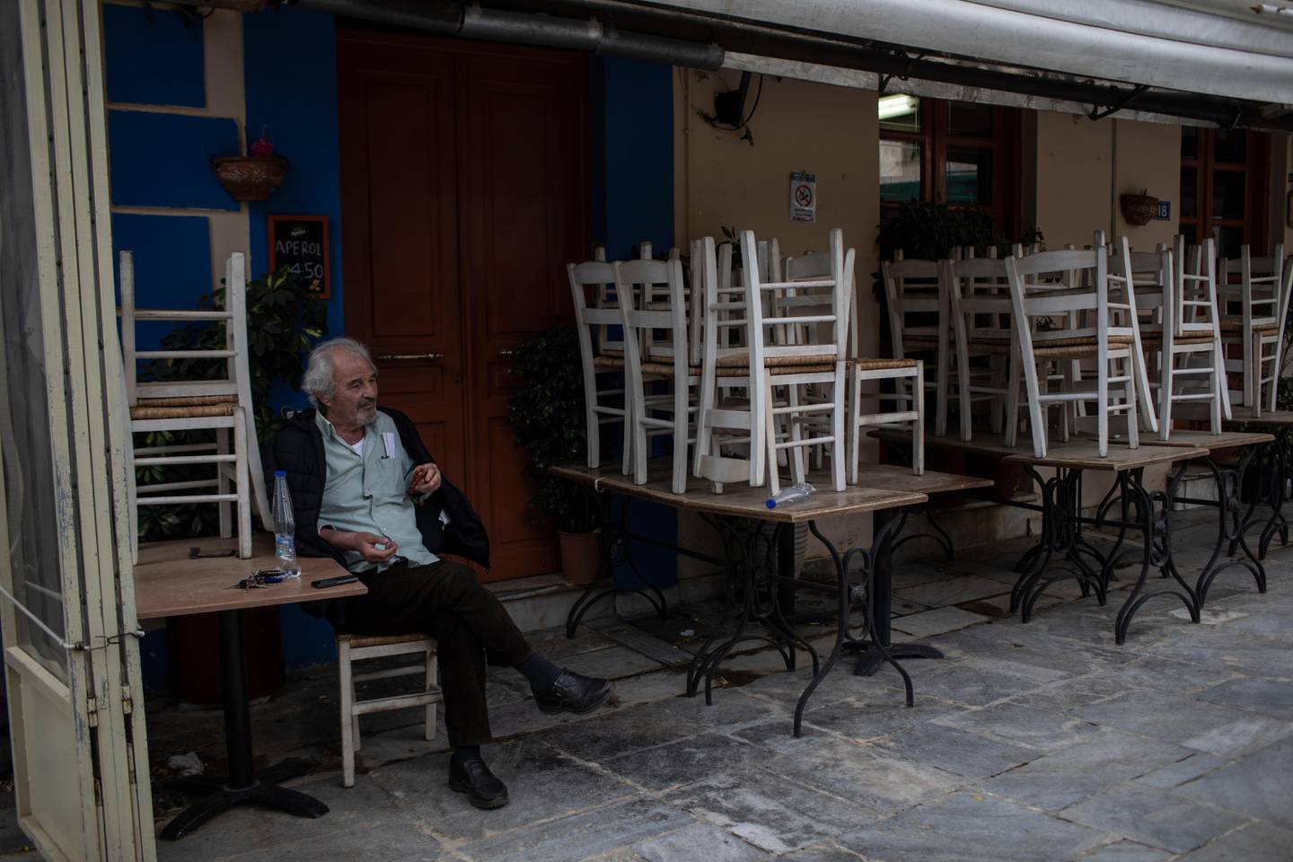 A man sits outside a closed restaurant in the traditional Plaka district of Athens, during lockdown measures to prevent the spread of the coronavirus, on Thursday, April 30, 2020. Greek authorities say the use of face masks will be compulsory on public transport and shops from May 4, when the country starts to ease its lockdown restrictions. (AP Photo/Petros Giannakouris)