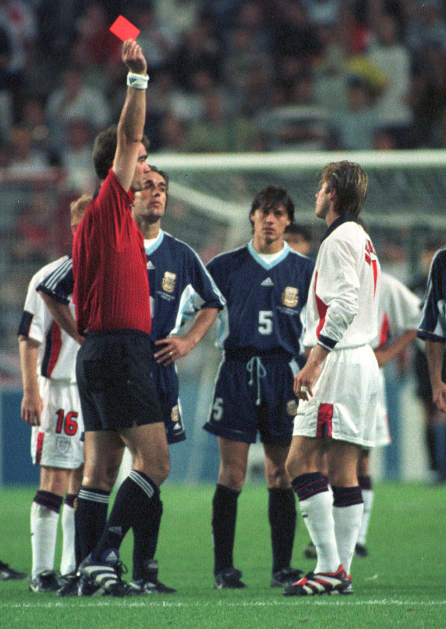 FILE - In this  June 30, 1998 file photo, England's David Beckham receives a red card from Danish referee Kim Milton Nielsen, during England's World Cup second round soccer match against Argentina, in Saint Etienne,  France. On this day: Beckham becomes public enemy number one in England, after he gets a red card for kicking Argentina's Diego Simeone. England lost on penalties after the match ended 2-2. (AP Photo/Denis Doyle, File)