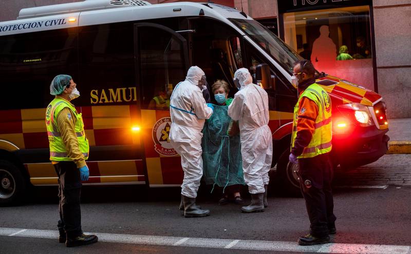 A patient, center, is transferred to a medicalised hotel during the COVID-19 outbreak in Madrid, Spain, Tuesday, March 24, 2020. For most people, the new coronavirus causes only mild or moderate symptoms. For some it can cause a more serious illness. (AP Photo/Bernat Armangue)