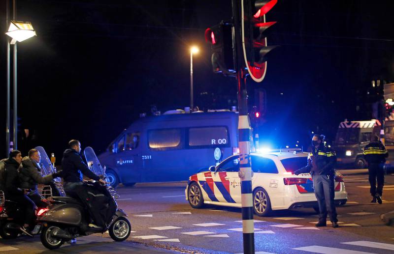 A police officers speaks to youths on scooters at a road block during a nation-wide curfew in Amsterdam, Netherlands, Tuesday, Jan. 26, 2021. The Netherlands entered its toughest phase of anti-coronavirus restrictions to date, imposing a nationwide night-time curfew from 9 p.m. until 4:30 a.m. which started Saturday Jan. 23, 2021, in a bid to control the COVID-19 infection rate. (AP Photo/Peter Dejong)