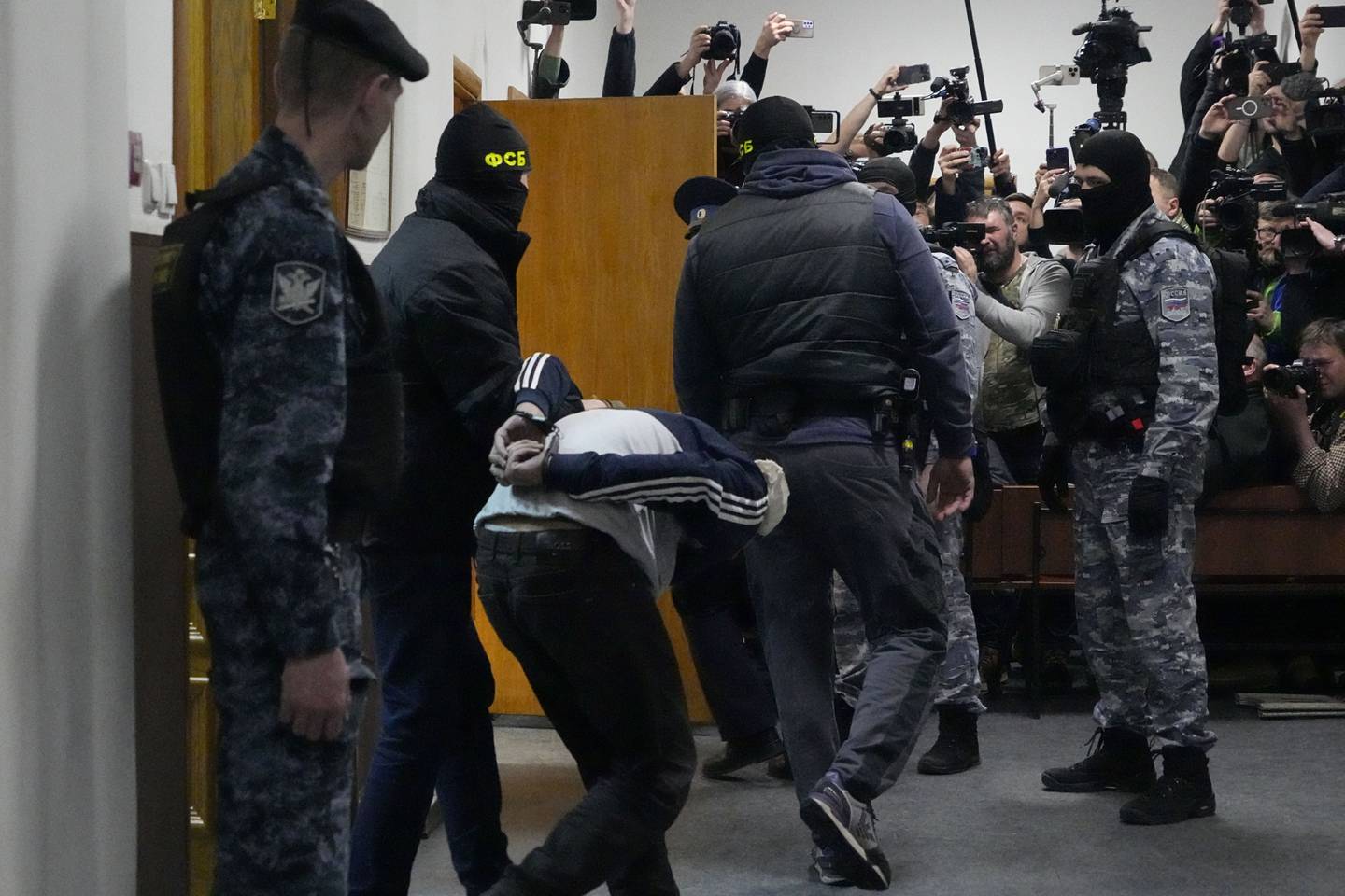 En av mennene som er siktet for angrepet mot konserthallen Crocus, føres inn i en rettssal i Moskva søndag kveld.