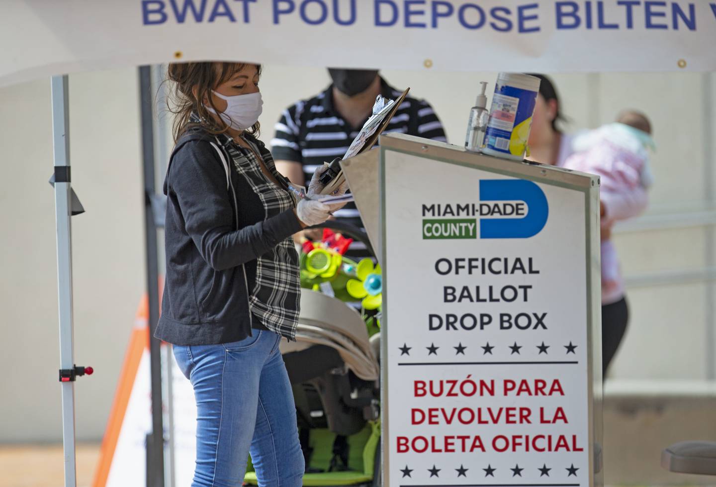 En valgfunksjonær legger stemmesedler i en offisiell valgboks i Miami 28. oktober 2020.
