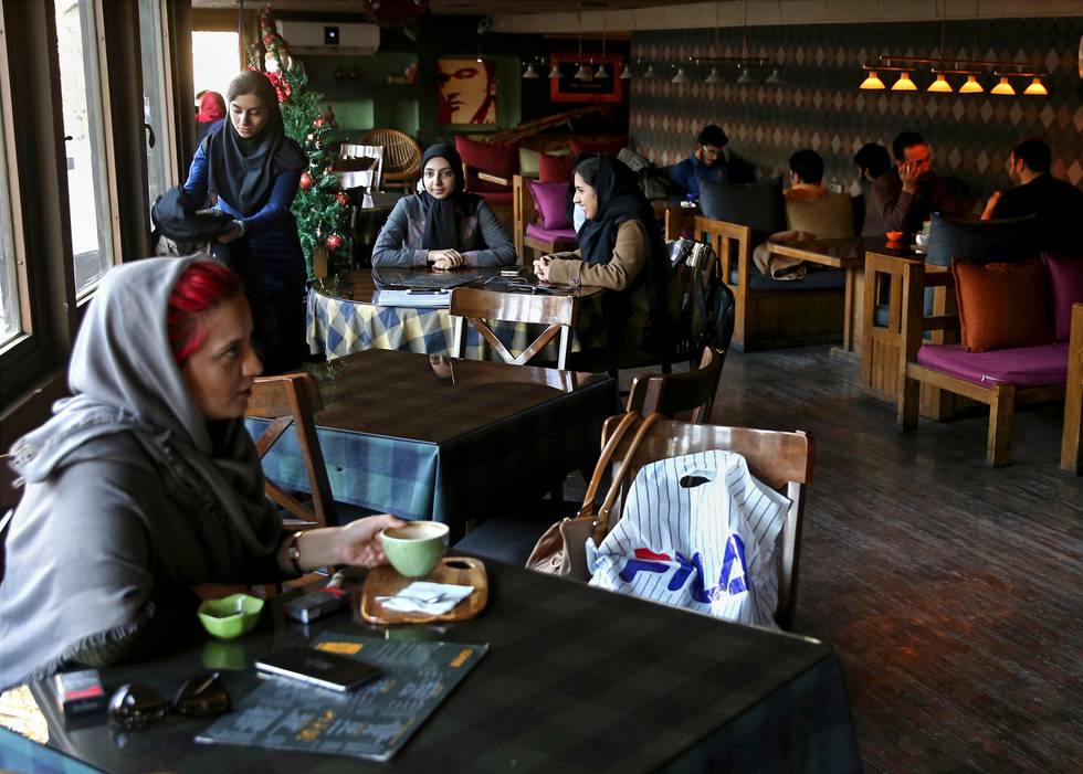 Young people spend their time at a cafe in downtown Tehran, Iran, Wednesday, Jan. 3, 2018. Tens of thousands of Iranians took part in pro-government demonstrations in several cities across the country on Wednesday, Iranian state media reported, a move apparently seeking to calm nerves after a week of protests and unrest that have killed at least 21 people. (AP Photo/Ebrahim Noroozi)